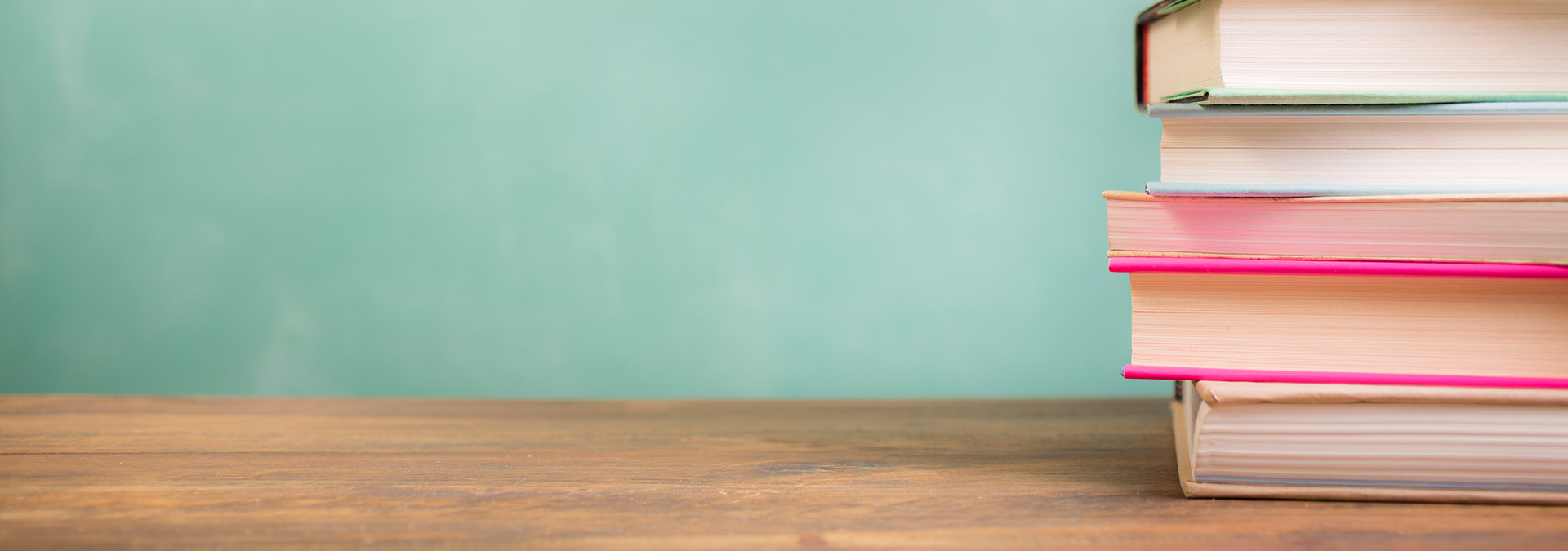 Vita und Qualifikation des Psychotherapeuten Thomas Leißing: Rechts im Anschnitt liegt, als Sinnbild für Fachwissen und Fortbildung, ein Stapel Bücher auf einer hölzerne Tischplatte vor einer türkisfarbenen Wand.